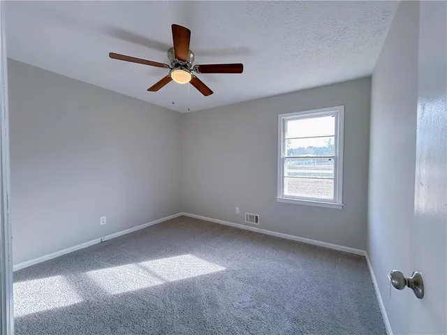 an empty room with a window and a ceiling fan