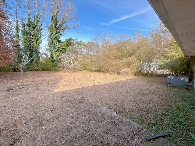 a view of dirt field with large trees