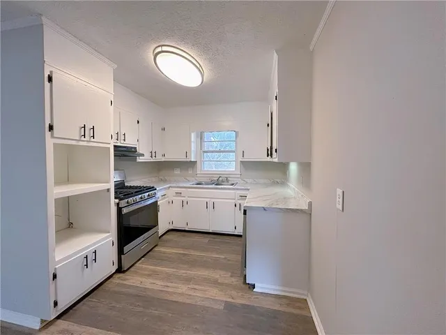 a kitchen with granite countertop white cabinets and white appliances