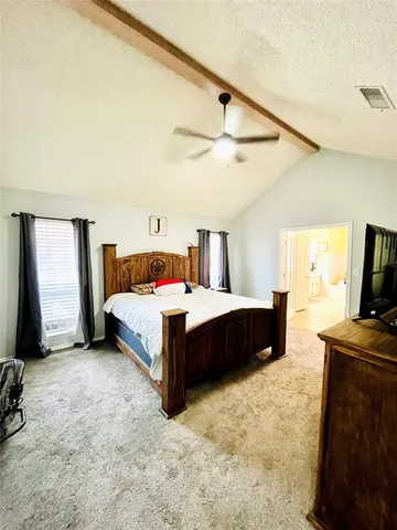 a bedroom with a bed and a flat tv screen on dresser
