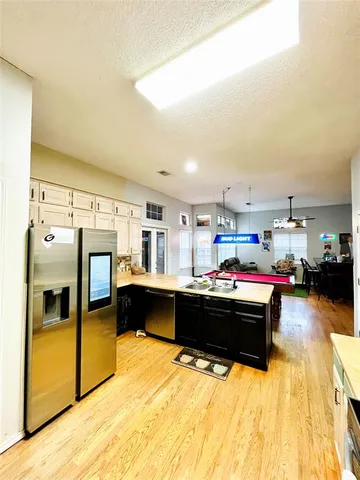 a kitchen view with stainless steel appliances kitchen island granite countertop a sink and white cabinets