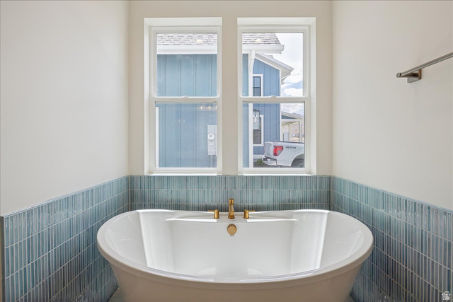 952 Mathilda Drive, Unit 156 Saratoga Springs, UT 84045 - Photo 12 of 25 Freestanding soaking tub with gold-finish fixtures set against a blue-toned vertical tile wainscoting