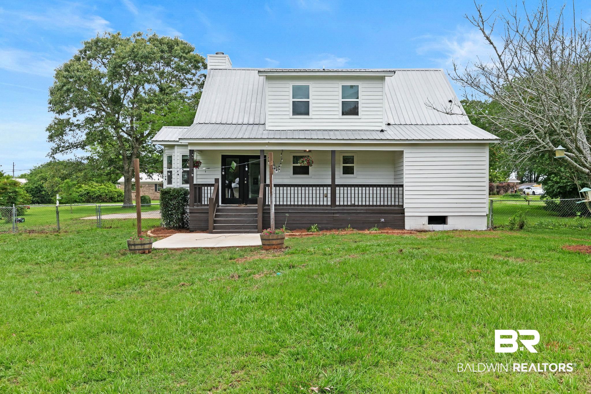 22810 High Ridge Road Fairhope, AL 36532 - Photo 52 of 78 White siding residence featuring a metal roof, dormer windows, and a covered porch with dark railings