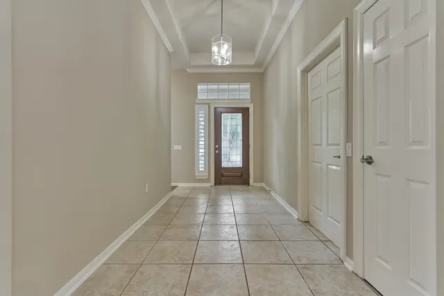 a view of a hallway with wooden floor and a chandelier