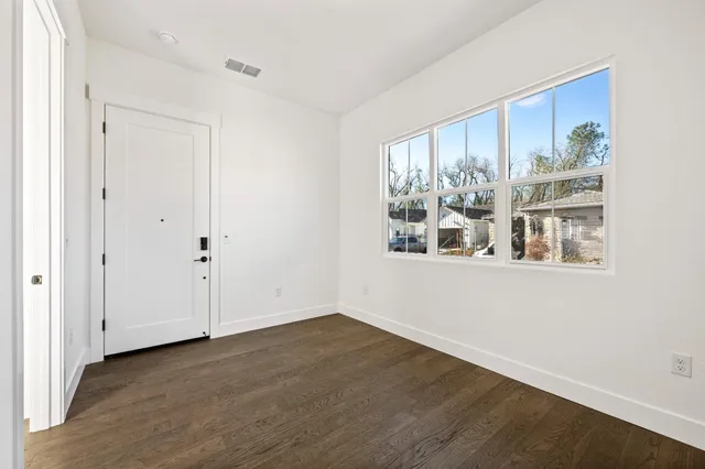 a view of an empty room with wooden floor and a window