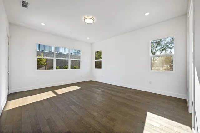 a view of empty room with wooden floor and fan