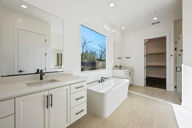 a spacious bathroom with a tub sink and mirror