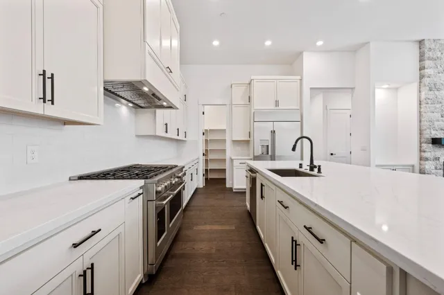 a large kitchen with stainless steel appliances granite countertop a sink a stove and a refrigerator