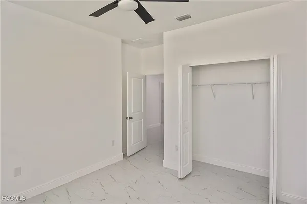 an empty room with a ceiling fan and carpet