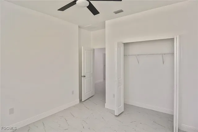 an empty room with a ceiling fan and carpet