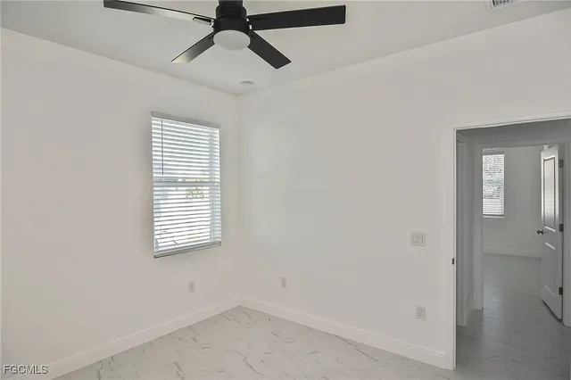 an empty room with a window and a ceiling fan