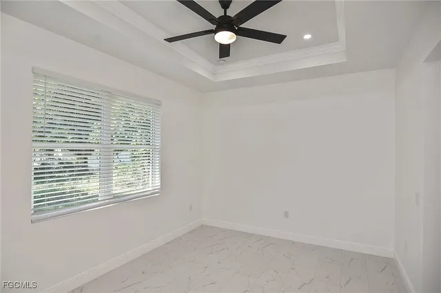an empty room with ceiling fan and windows