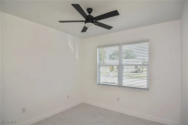 an empty room with a window and a ceiling fan
