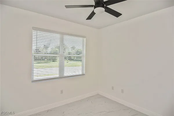 an empty room with a window and a fan
