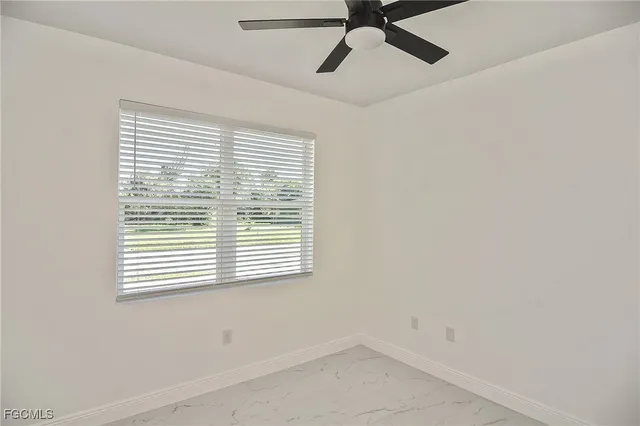 an empty room with a window and a fan