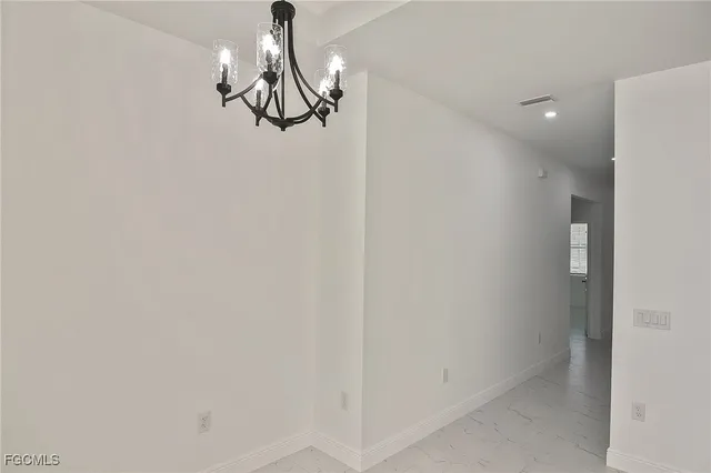 a glass door with a chandelier fan and kitchen view