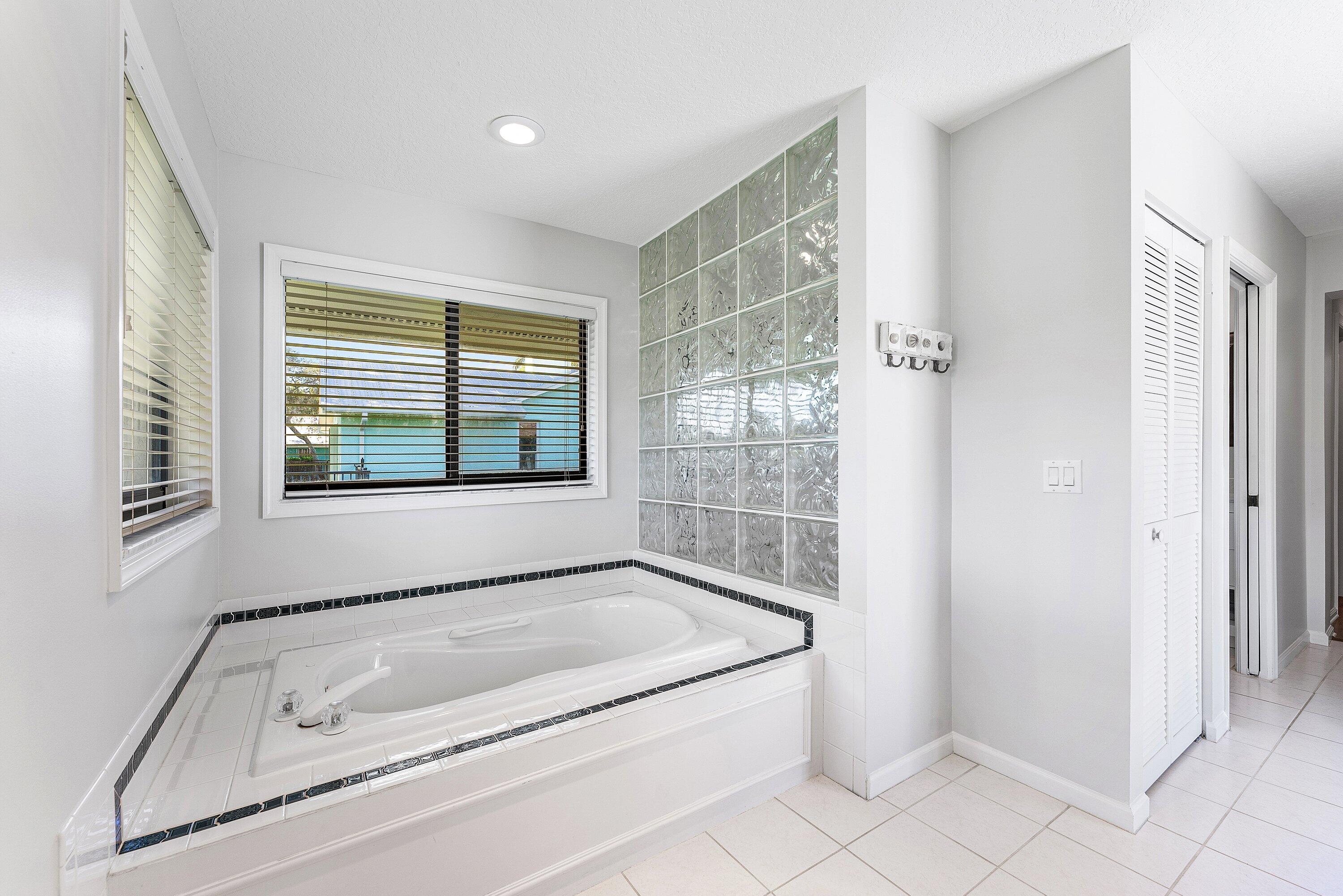 6048 Wood Lake Road Jupiter, FL 33458 - Photo 15 of 31 a bathroom with a tub a sink and a window
