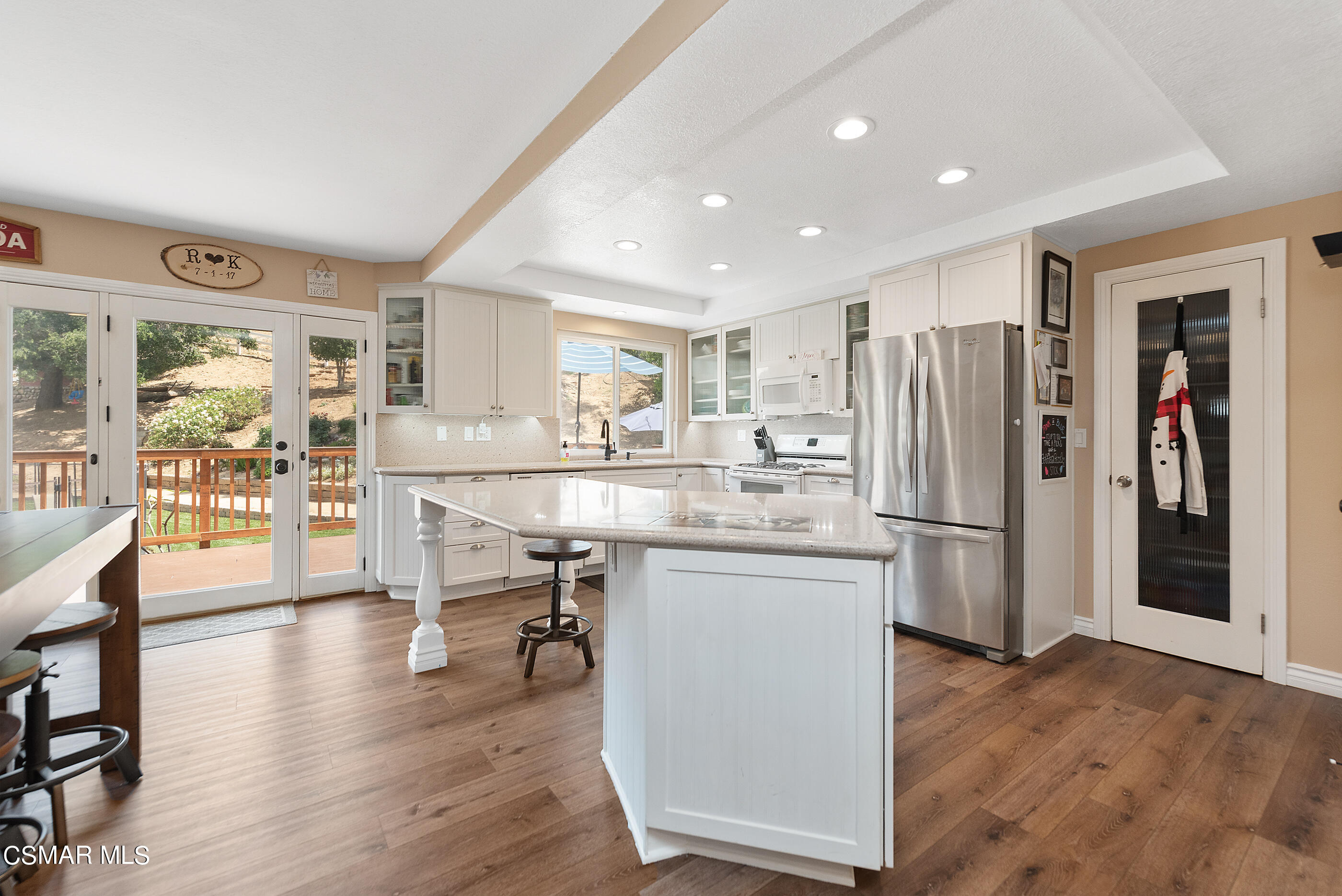1137 Rambling Road Simi Valley, CA 93065 - Photo 11 of 77 a kitchen with stainless steel appliances kitchen island granite countertop a refrigerator a stove a sink a dining table and chairs with wooden floor