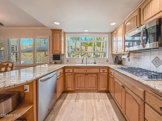 a kitchen with stainless steel appliances granite countertop a stove a sink and a granite counter tops with wooden floors