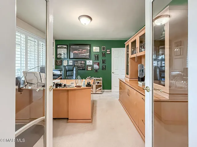 a view of a workspace with furniture and a large window