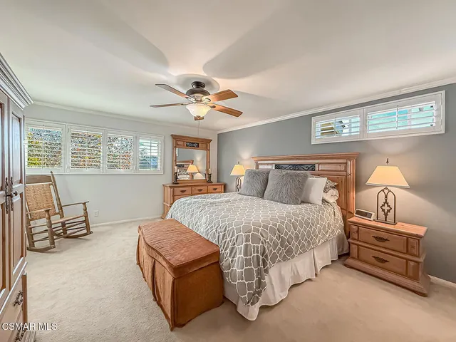 a spacious bedroom with a bed a couch and large windows