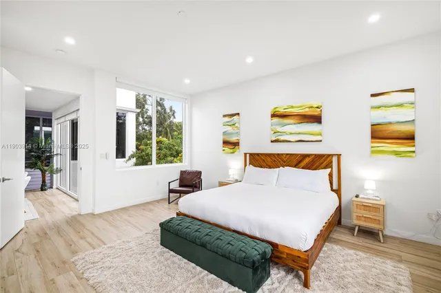 a bedroom with a bed a dresser and a large window
