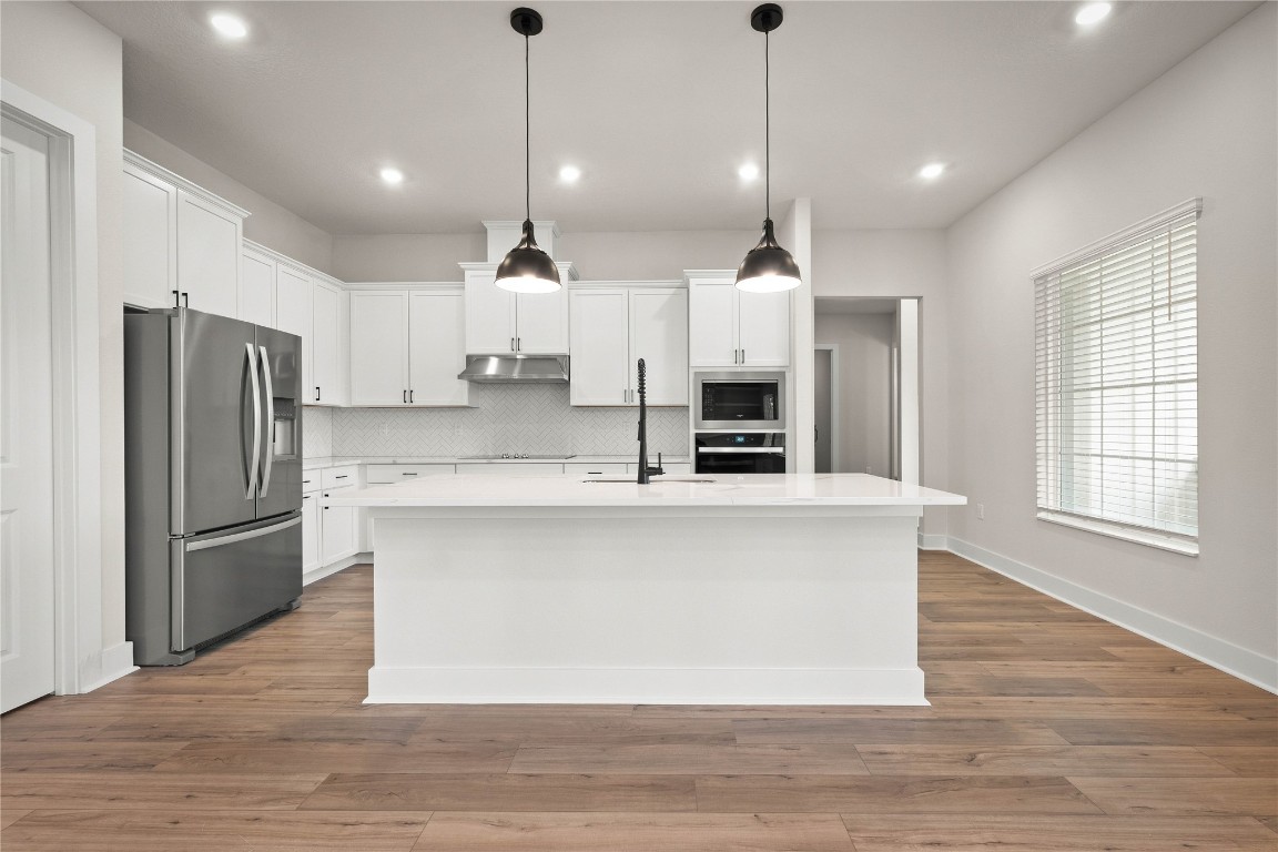 36199 Pitch Lane Hilliard, FL 32046 - Photo 22 of 40 a large kitchen with stainless steel appliances a large counter top a refrigerator a sink and a wooden floor