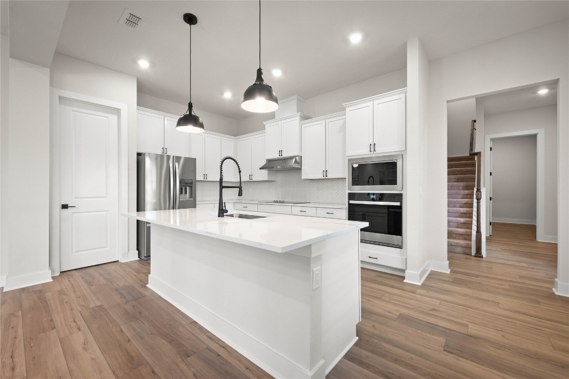 36199 Pitch Lane Hilliard, FL 32046 - Photo 23 of 40 a kitchen with kitchen island a sink stainless steel appliances and wooden floor