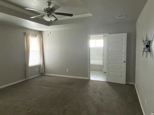 an empty room with windows and fan