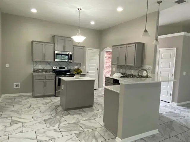 a kitchen with kitchen island stainless steel appliances a stove a sink a microwave a counter top and cabinets