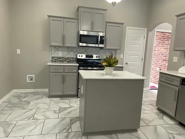 a kitchen with stainless steel appliances granite countertop a stove a sink and a microwave