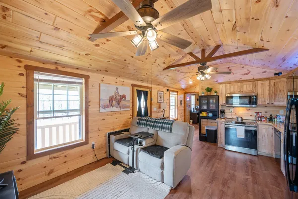 a living room with stainless steel appliances kitchen island granite countertop furniture and a wooden floor