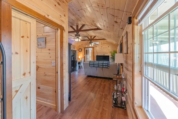 a view of a hallway with wooden floor and a living room
