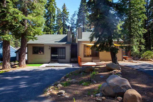 a front view of a house with garden and trees