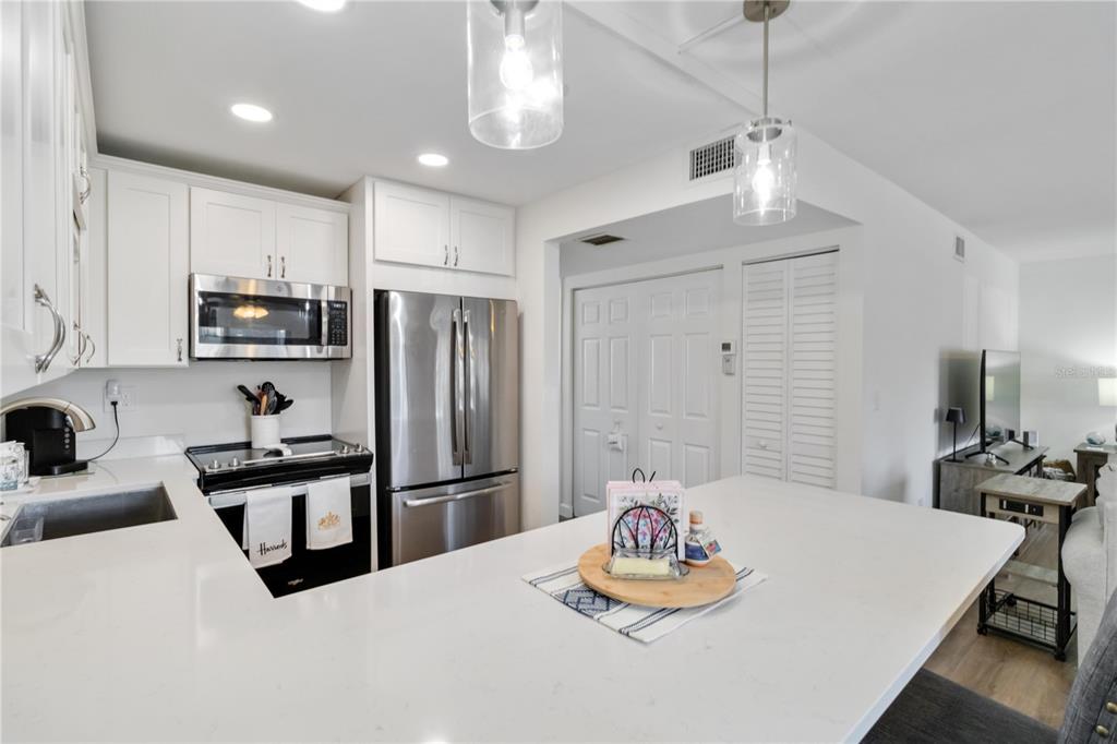 5416 Swift Road, Unit 27 Sarasota, FL 34231 - Photo 19 of 55 a kitchen with stainless steel appliances granite countertop a refrigerator a stove a sink dishwasher a dining table and chairs with wooden floor