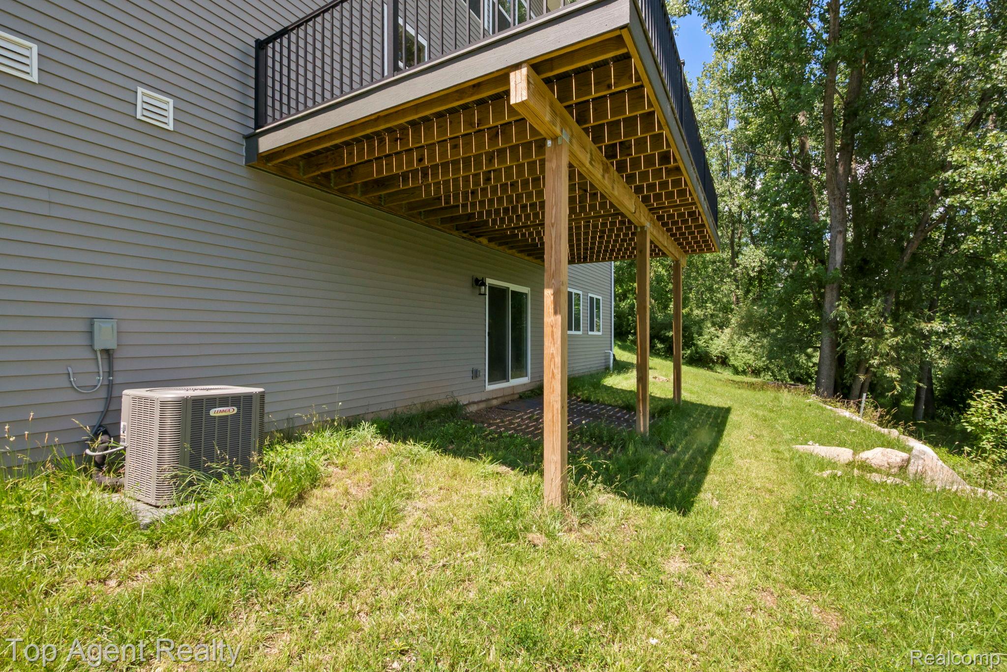 63770 Dequindre Road Washington, MI 48095 - Photo 58 of 61 Rear exterior featuring a spacious elevated deck with black metal railings, a ground-level patio area, and a sliding glass door