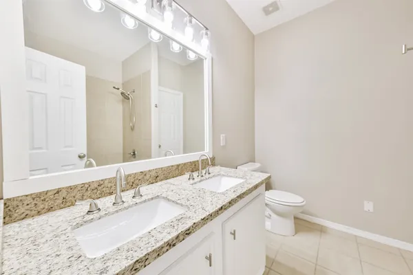 a bathroom with a granite countertop sink a toilet and a mirror
