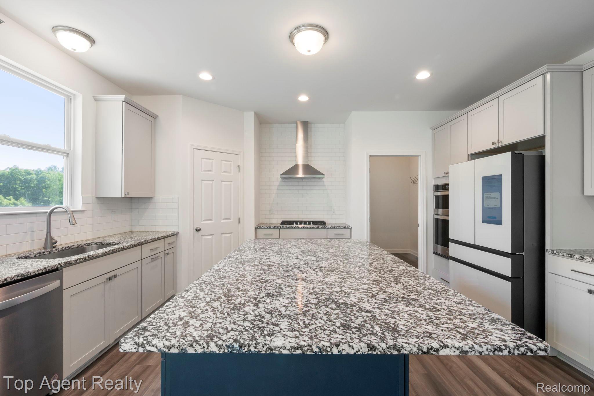 63770 Dequindre Road Washington, MI 48095 - Photo 18 of 61 Kitchen featuring a large island with a speckled countertop, white subway tile backsplash, stainless steel appliances, and wood-finish flooring
