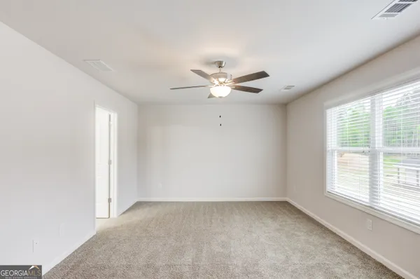 an empty room with a ceiling fan and a window