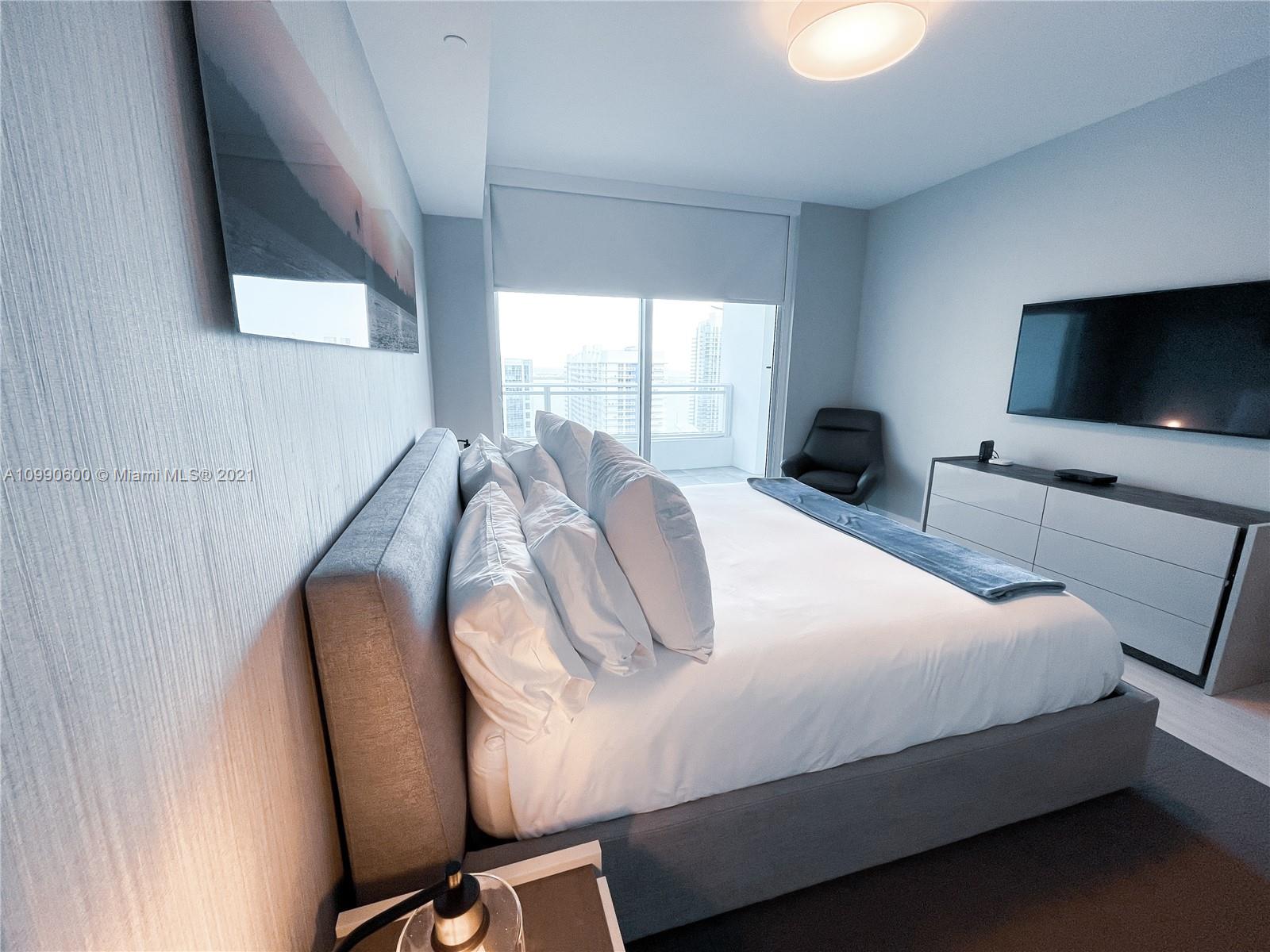 1080 Brickell Avenue, Unit 3702 Miami, FL 33131 - Photo 15 of 39 a bedroom with a bed and large flat screen tv