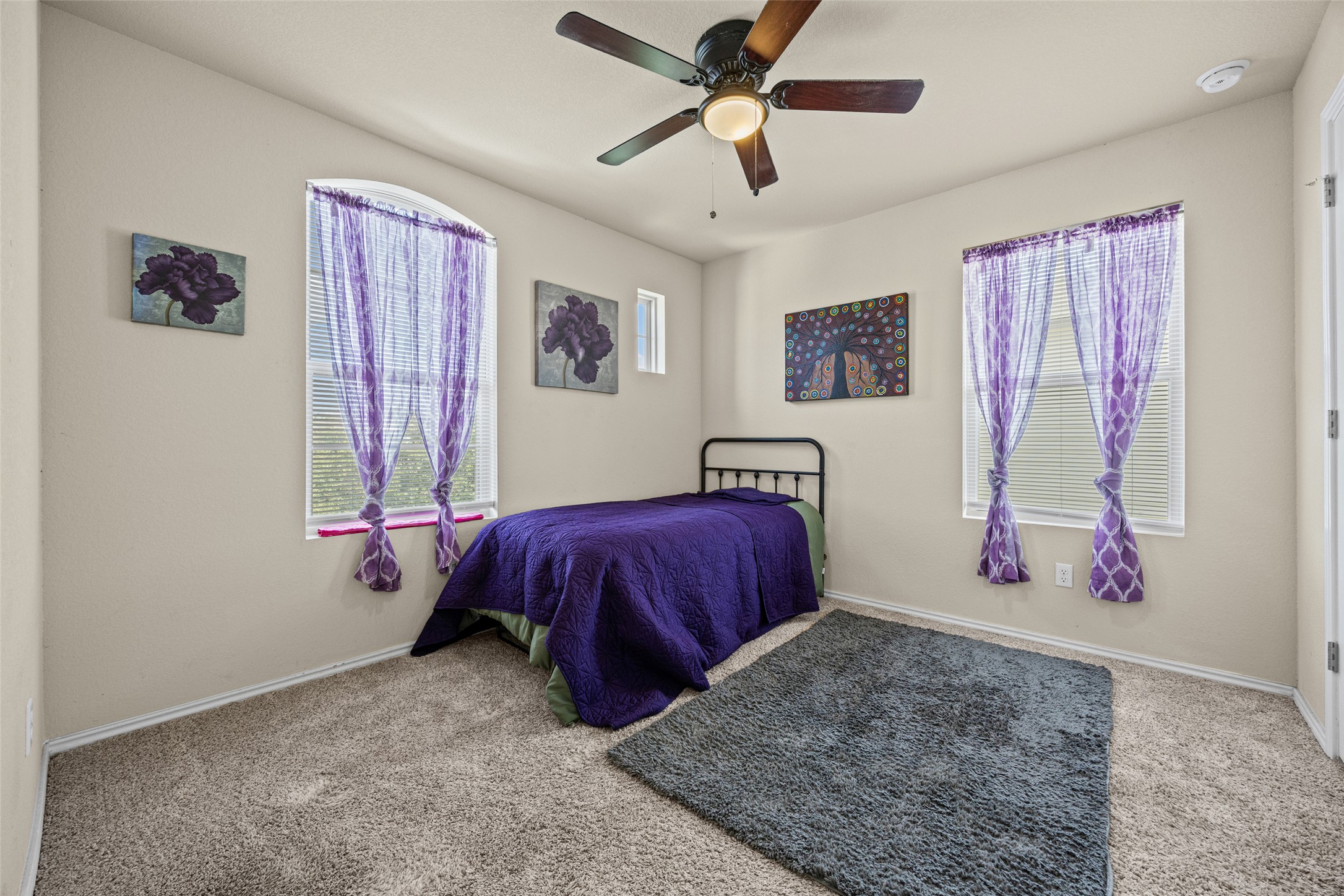 19113 Rookery Trail Pflugerville, TX 78660 - Photo 13 of 36 Carpeted interior space featuring a ceiling fan with integrated lighting, two rectangular windows with blinds, and one arched window with blinds