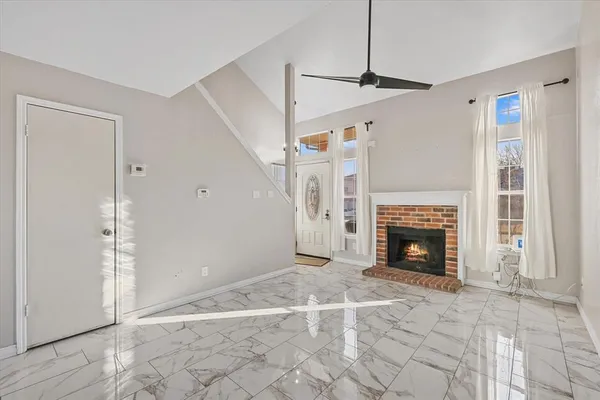 a view of an empty room with wooden floor fireplace and a window