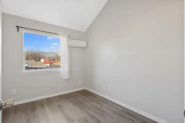 a view of an empty room with wooden floor and window