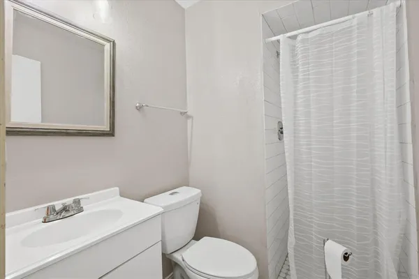 a white toilet sitting next to a white sink and vanity