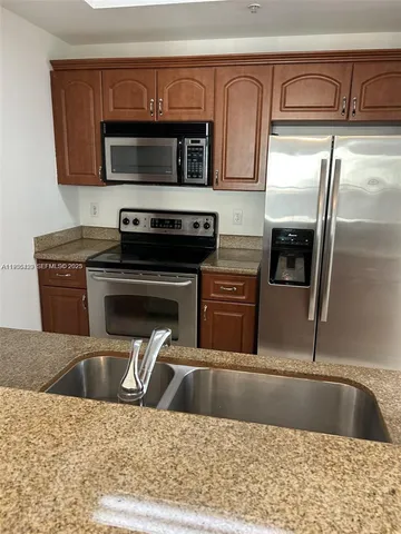 a kitchen with stainless steel appliances granite countertop a refrigerator and a stove