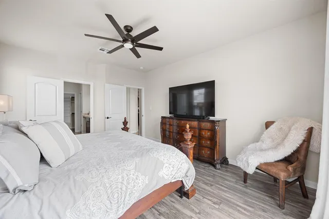 a spacious bedroom with a bed and wooden floor