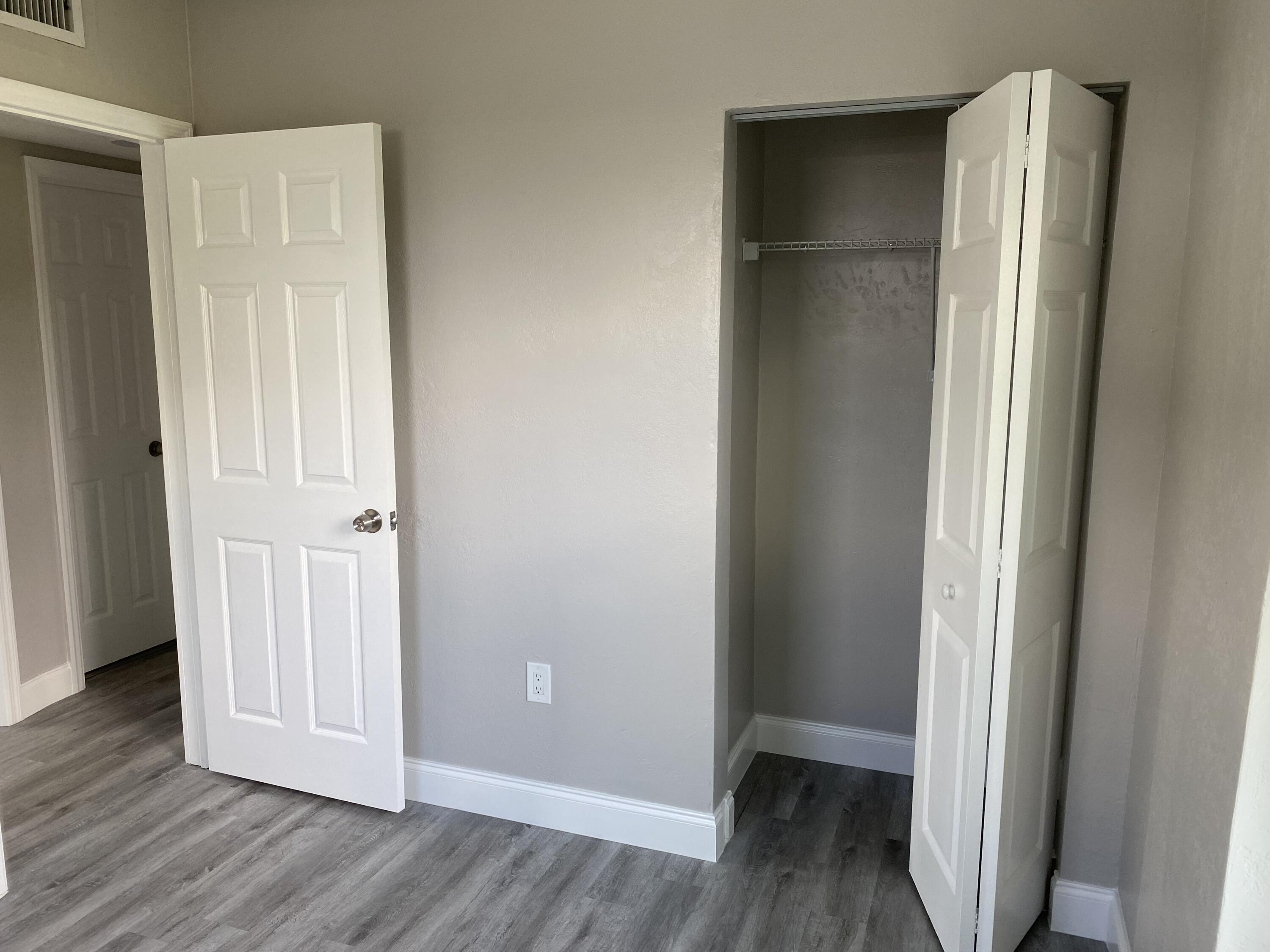 an empty room with wooden floor and closet area