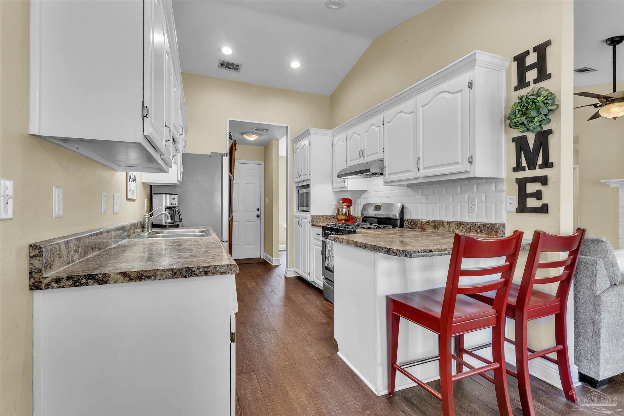 4321 Ridgeland Drive Pace, FL 32571 - Photo 8 of 36 a kitchen with stainless steel appliances granite countertop a white cabinets and wooden floor