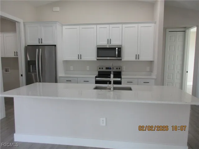 a kitchen with stainless steel appliances a refrigerator a stove a sink and white cabinets
