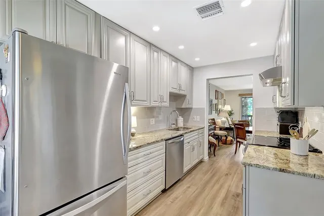 a kitchen with granite countertop a sink stainless steel appliances and cabinets